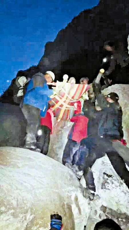 救援隊(duì)員用自制的簡(jiǎn)易擔(dān)架抬傷者。