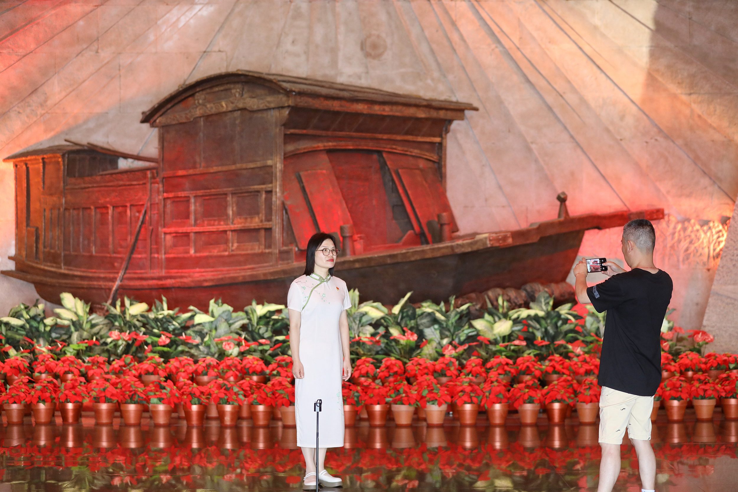 2025年6月24日，浙江嘉興，游客在南湖革命紀(jì)念館與紅船雕塑合影。（圖片來源：視覺中國）