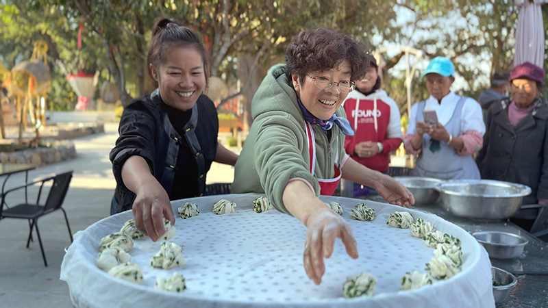 【2】旅居者趙發(fā)英（圖左二）教曼海村村民做花卷。陶思源-攝